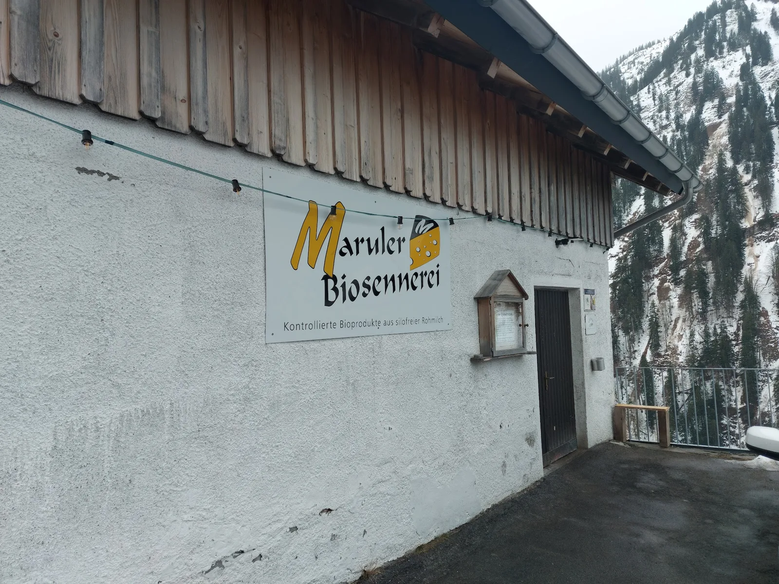 Firmenschild der Maruler Bio-Sennerei vor der Bergkulisse